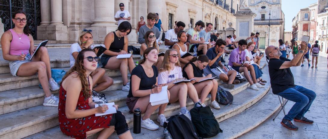 Students sit on steps in Sicily to draw